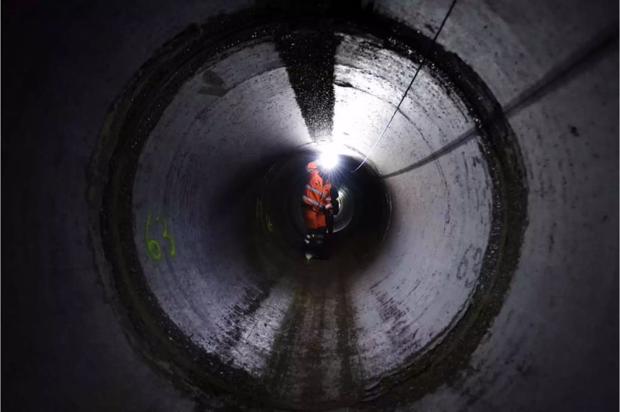 Mitarbeiter mit Stirnlampe in Ablaufleitung in Basler Kläranlage - Keystone