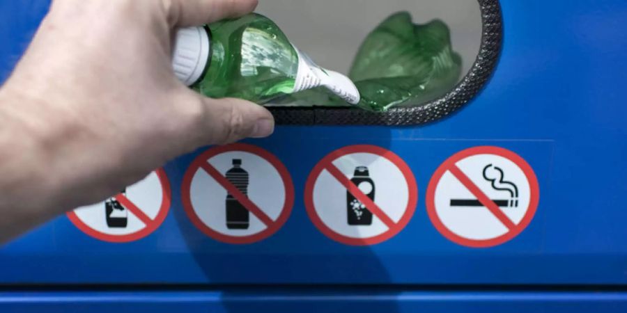 Hand gibt PET-Flasche in eine PET-Recycling-Tonne - Keystone