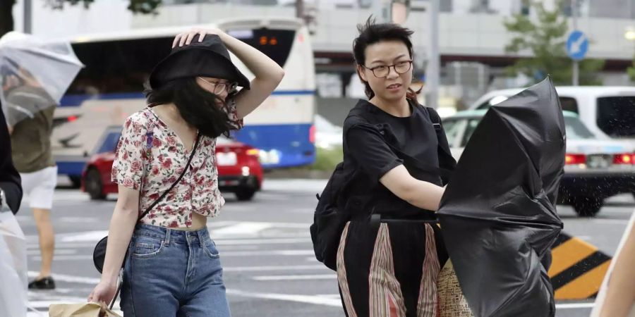 Frauen überqueren eine Strasse in Nagoya (Japan) bei starkem Wind.