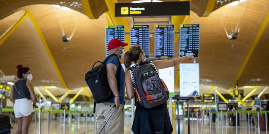 Reisende in einer Halle im Flughafen Madrid-Barajas. Foto: Manu Fernandez/AP/dpa