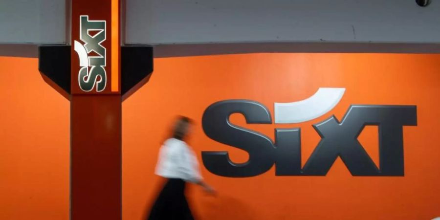 Eine Frau geht während eines Fotoshooting für die Deutsche Presse Agentur am Logo des Autovermieters Sixt vorbei. Foto: Peter Kneffel/dpa