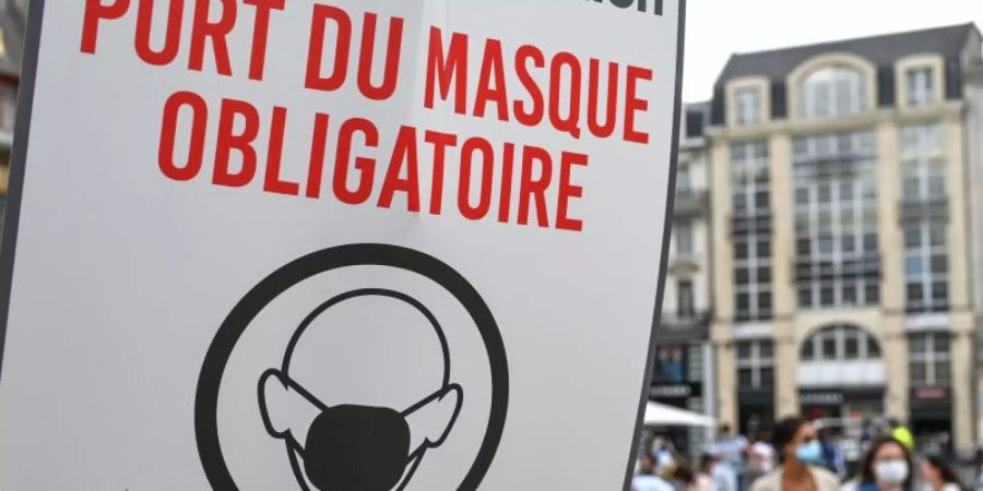 In einer Fussgängerzone von Lille weist ein Schild auf die Maskenpflicht hin. Foto: Denis Charlet/AFP/dpa/Archiv