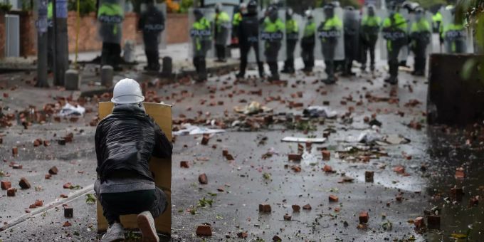 Ein regierungskritischer Demonstrant steht in Kolumbien diversen Polizisten gegenüber. kolumbien