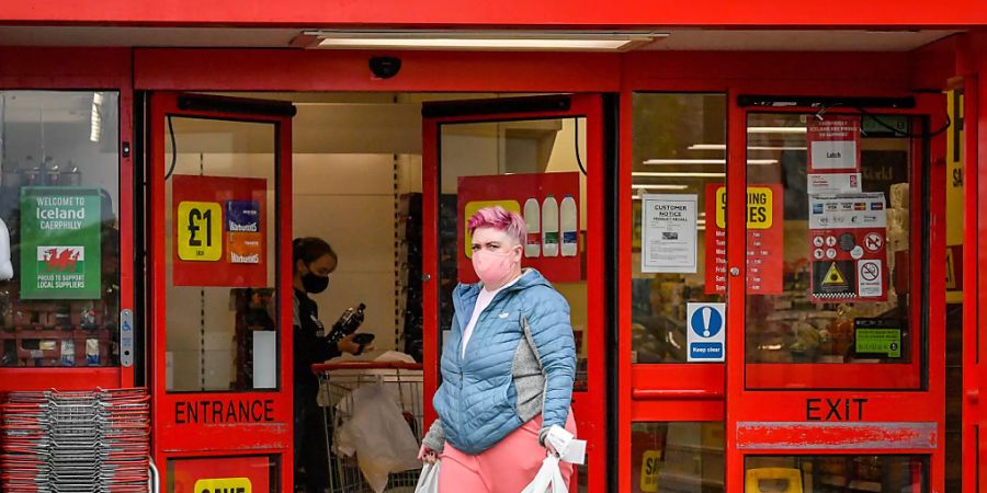 ARCHIV - Eine Frau mit Mundschutz verlässt einen Supermarkt im britischen Caerphilly. Foto: Ben Birchall/PA Wire/dpa