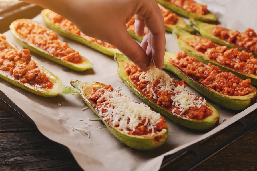 Gefüllte Zucchini wird mit Käse bestreut