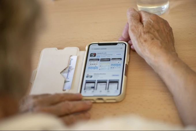 Seniorin installiert App am Tisch
