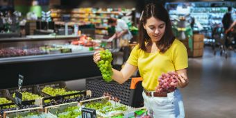 Frau im Supermarkt wählt Trauben aus