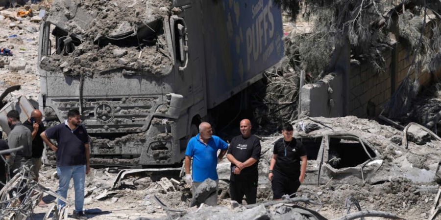 ARCHIV - Menschen versammeln sich an der Stelle eines zerstörten Gebäudes, das bei einem israelischen Luftangriff im Dorf Qannarit im Südlibanon getroffen wurde. Foto: Mohammed Zaata...