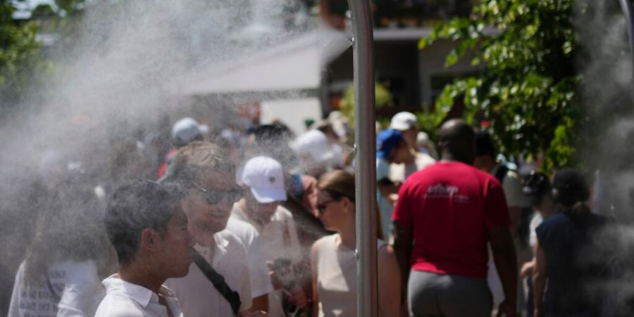 French Open-Besucher kühlen sich an einem heißen Tag mit Wasser aus Sprinklern ab. Foto: Christophe Ena/AP/dpa