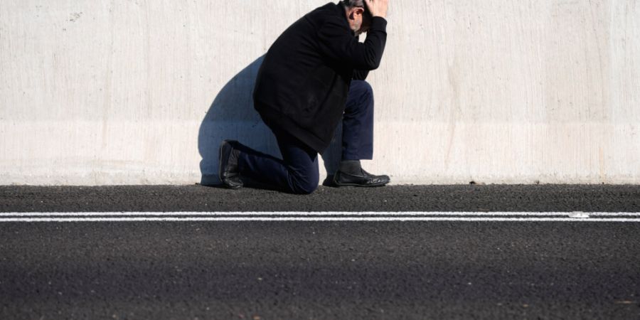dpatopbilder - Ein Mann geht am Straßenrand in Deckung, als eine Luftschutzsirene vor einem bevorstehenden iranischen Raketenangriff in Tel Aviv warnt. Foto: Ohad Zwigenberg/AP/dpa