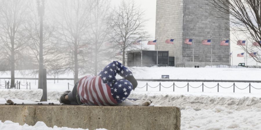 dpatopbilder - Ein Obdachloser ruht sich in der Nähe des Washington Monuments auf einem warmen Lüftungsschacht aus, um sich zu wärmen. Foto: Mehmet Eser/SOPA Images via ZUMA Press Wi...
