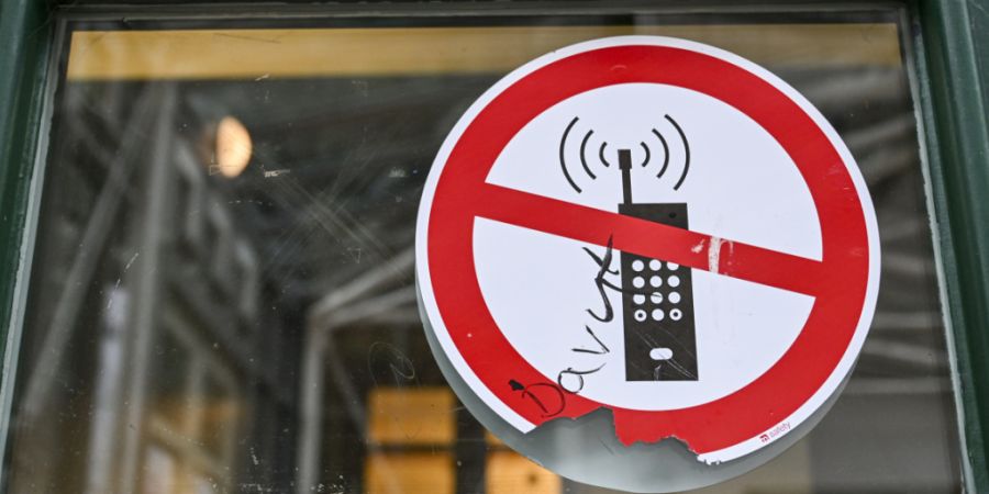 ARCHIV - Ein Schild mit einem durchgestrichenen Handysymbol weist in einer Schule auf das Handyverbot hin. Foto: Jens Kalaene/dpa/Symbolbild