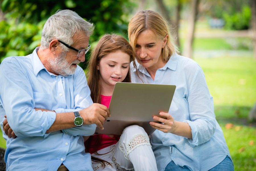 Glückliche Familie mit Laptop im öffentlichen Park.