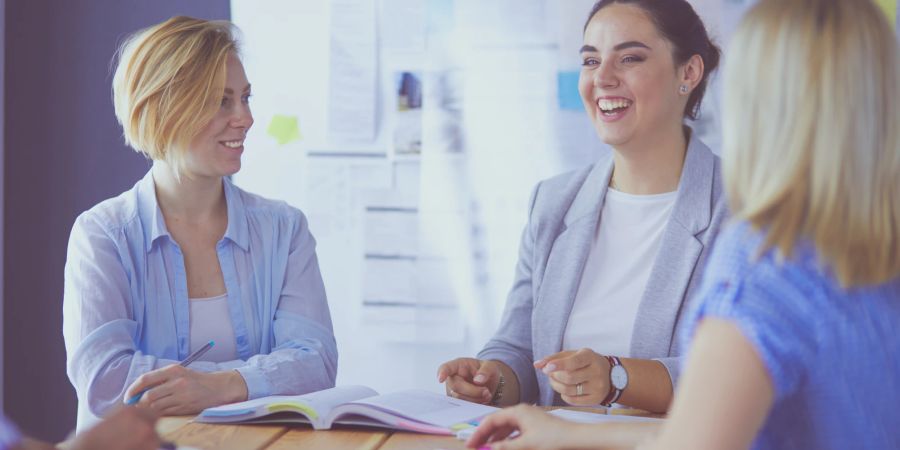 Glückliche Kolleginnen in der Besprechung.