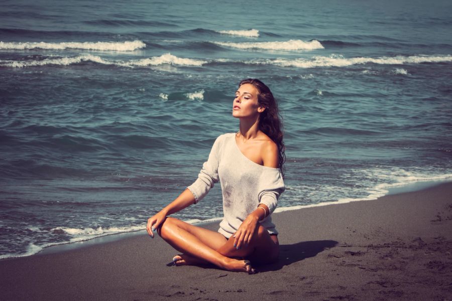 Frau praktiziert Yoga am Strand und Meer