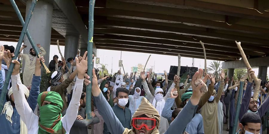 Anhänger von TLP-Parteiführer Rizvi halten während eines Protests Bambusstöcke und Steine in die Höhe. Foto: Muhammad Sajjad/AP/dpa