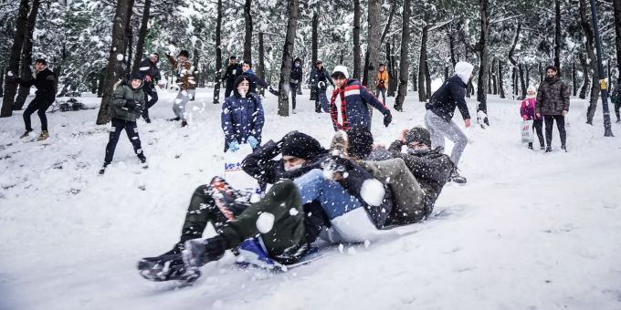 Menschen rodeln bei starkem Schneefall am Camlica-Hügel in Istanbul. Winterwetter in der Türkei