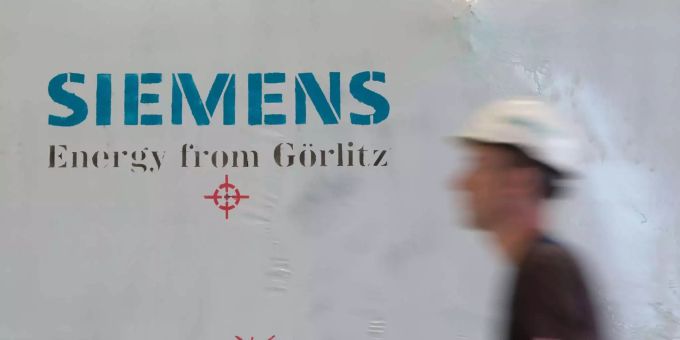 Ein Siemens-Mitarbeiter mit Schutzhelm geht in einer Montagehalle des Siemens-Turbinenwerks an einer Folie mit dem Aufdruck «Siemens Energy from Görlitz» vorbei.