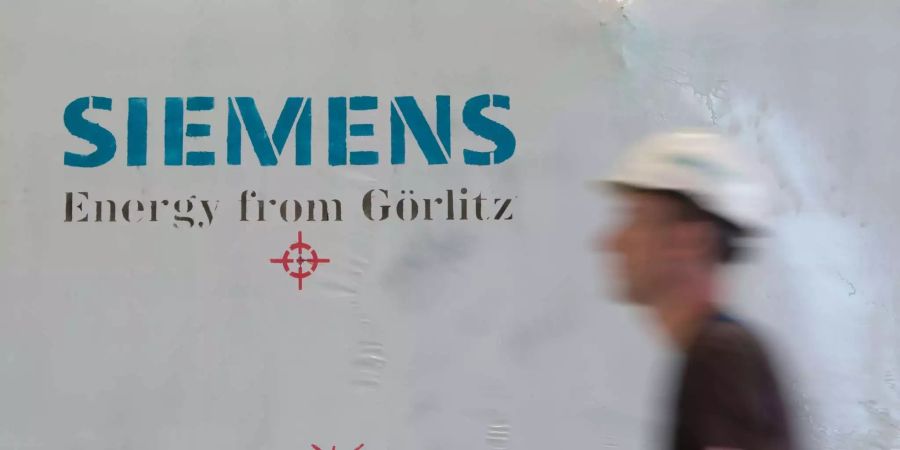 Ein Siemens-Mitarbeiter mit Schutzhelm geht in einer Montagehalle des Siemens-Turbinenwerks an einer Folie mit dem Aufdruck «Siemens Energy from Görlitz» vorbei.