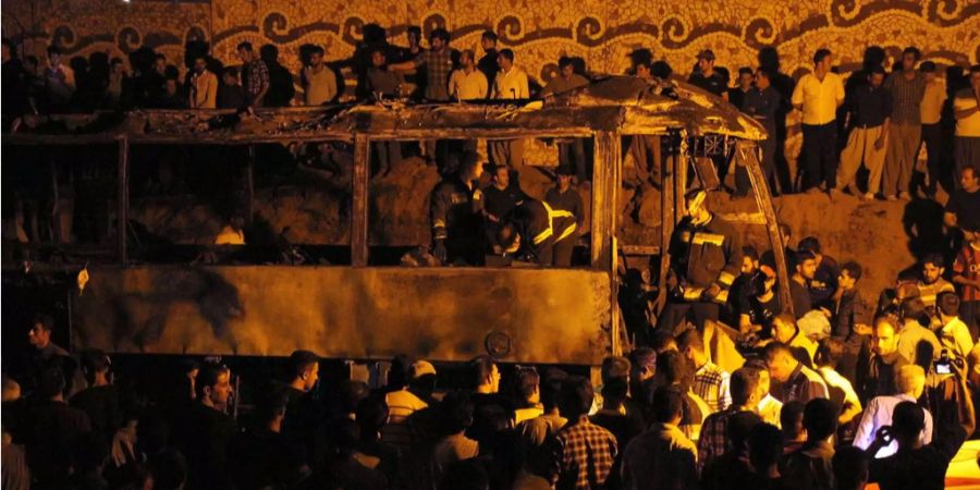 Die Iranische Feuerwehr und Passanten zwischen einem Bus und einem PKW im Westen Irans.