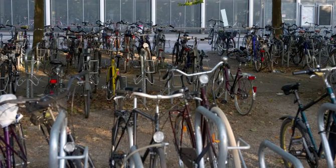 Fahrräder stehen am Bahnhof vor einem Fahrradparkhaus.