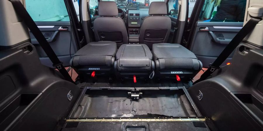 Ein sichergestelltes Kurierfahrzeug der Mafia mit einem eingebauten Versteck unter den Sitzen steht während einer Pressekonferenz in einer Werkstatt.