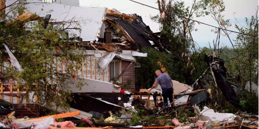 Ein Mann sammelt persönliche Gegenstände aus einem beschädigten Haus auf, nachdem ein Tornado wütete.