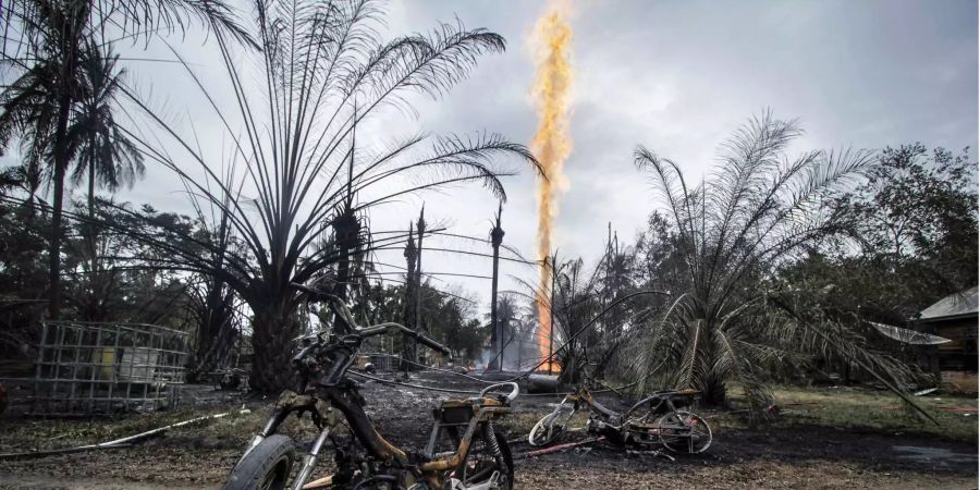 Zwei verbrannte Motorräder stehen auf einem von Feuer gezeichneten Ölfeld im Dorf Pasir Putih.