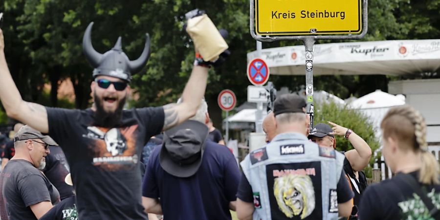 Festival-Besucher posieren vor dem Ortseingangsschild. Nach pandemiebedingter Pause findet vom 4. bis 6. August 2022 wieder das Heavy-Metal-Festival Wacken Open Air in Schleswig-Holstein statt. Foto: Frank Molter/dpa