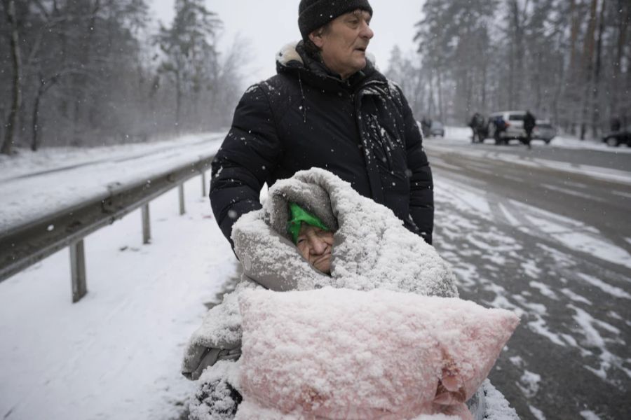 Eine ältere Frau wird aus Irpin evakuiert. Wegen der Kälte ist sie mit Schnee bedeckt.