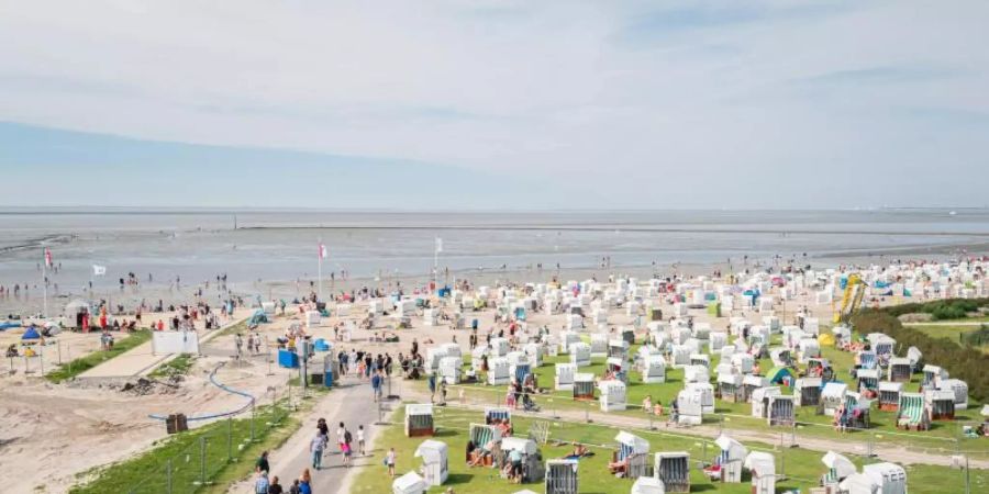 Bei sommerlichen Temperaturen zieht es viele an den Badestrand von Norddeich. Foto: Mohssen Assanimoghaddam/dpa