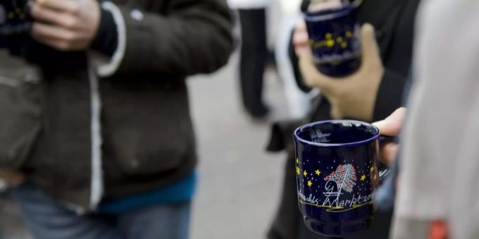 Besucher eines Weihnachtsmarktes trinken Glühwein. (Symbolbild) Glühwein Coronavirus