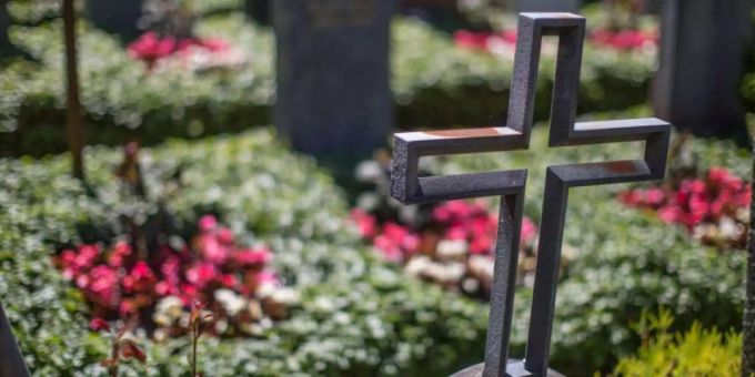 Ein Kreuz steht bei einem Grab auf einem Friedhof. coronavirus