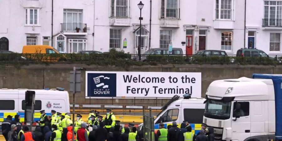 Die Polizei hält Fahrer zurück, die versuchen, in den Hafen von Dover zu laufen. Am englischen Hafen Dover ist es zwischen wartenden Lkw-Fahrern und der Polizei zu Schubsereien und Handgemenge gekommen. Foto: Steve Parsons/PA Wire/dpa