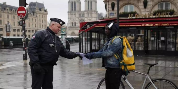Ein französischer Polizeibeamter überprüft in Paris die Genehmigung eines Passanten, sich weiter als einen Kilometer vom Wohnort zu entfernen. Foto: Francois Mori/AP/dpa Ein französischer Polizeibeamter überprüft in Paris die Genehmigung eines Passanten, sich weiter als einen Kilometer vom Wohnort zu entfernen. Foto: Francois Mori/AP/dpa