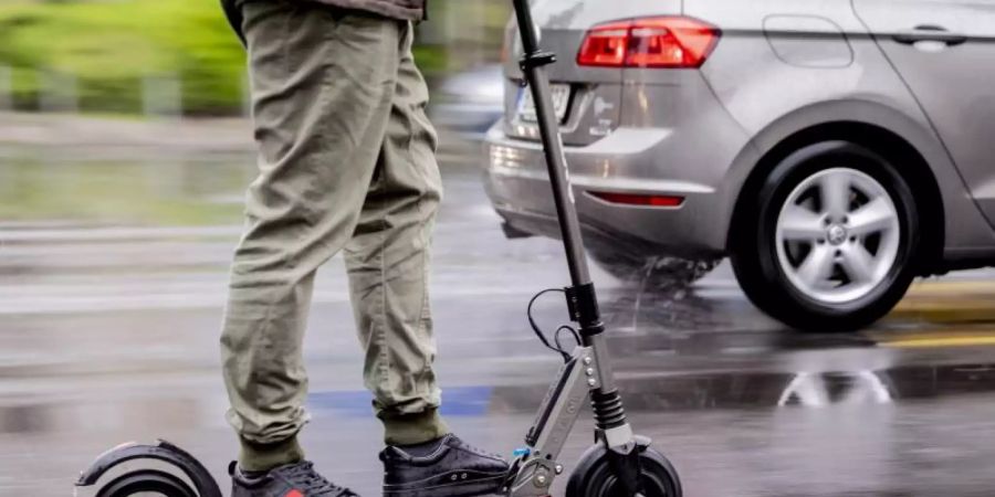 Ein Mann fährt mit einem E-Scooter auf der Strasse. Foto: Christoph Soeder/dpa