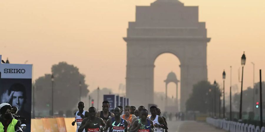Teilnehmer des Halbmarathons vor dem «India Gate» in Neu Delhi. Foto: Altaf Qadri/AP/dpa