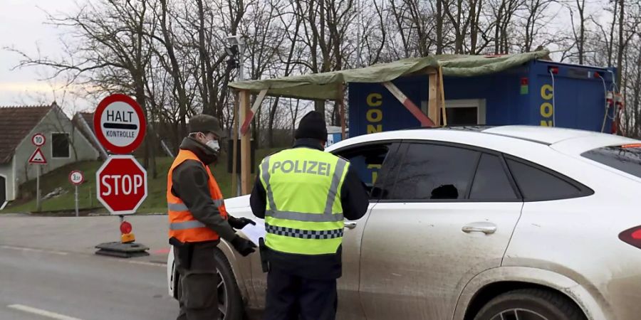 Ein Soldat der österreichischen Armee und ein Polizist kontrollieren einen Autofahrer nach der Grenzüberquerung von Tschechien nach Österreich. Österreich hat die Einschränkungen zur Eindämmung der Corona-Pandemie verschärft. Foto: Ronald Zak/AP/dpa