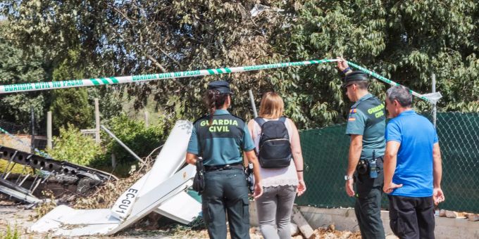 Ein Mitglied der Polizeieinheit «Guardia Civil» hält einer Frau das Absperrband zu einer Absturzstelle mit Wrackteilen hoch, so dass sie diese betreten kann. mallorca hubschrauber