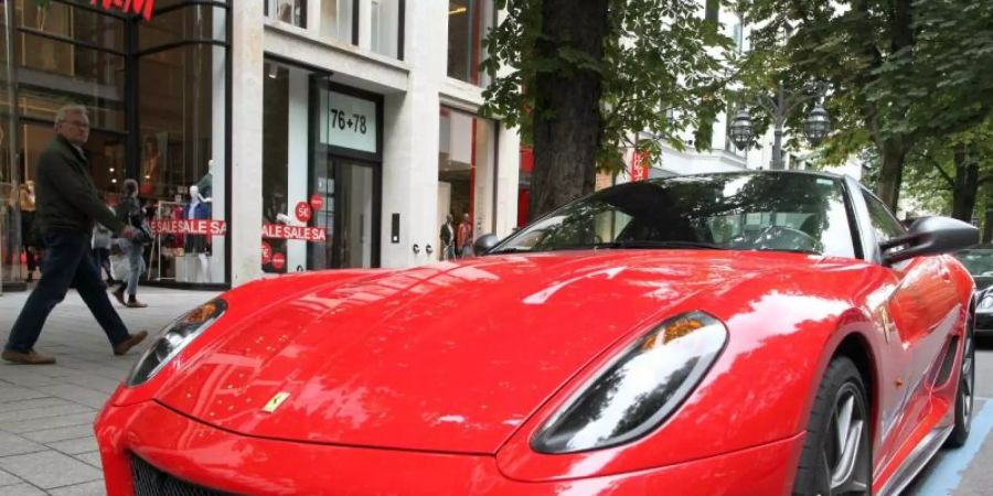 Ein Ferrari parkt auf der Königsallee in Düsseldorf, die als Laufsteg der Reichen und Schönen gilt. Foto: Martin Gerten