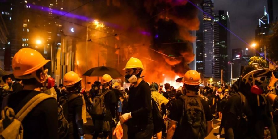 Demonstranten vor einer brennenden Barrikade in Hongkong