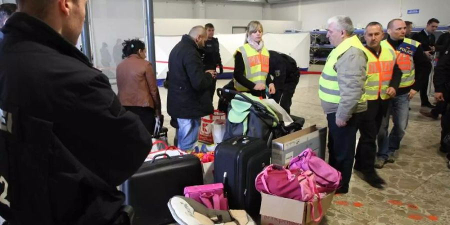 Polizisten begleiten abgelehnte Asylbewerber zu einem Terminal. Foto: Sebastian Willnow