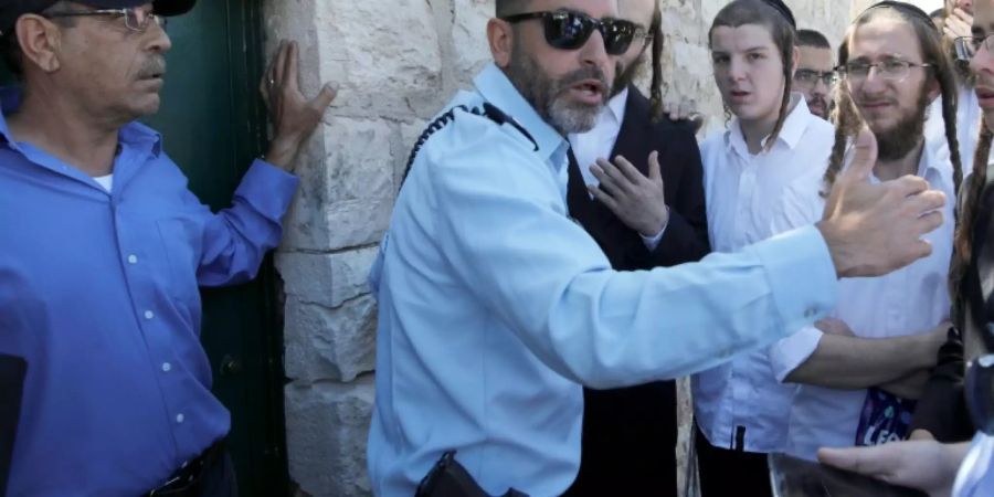 An Israeli policeman prevents Ultra-Orthodox Jewish men from entering the Tombs of the Kings site in Jerusalem owned and administered by the French consulate because they did not pre-register