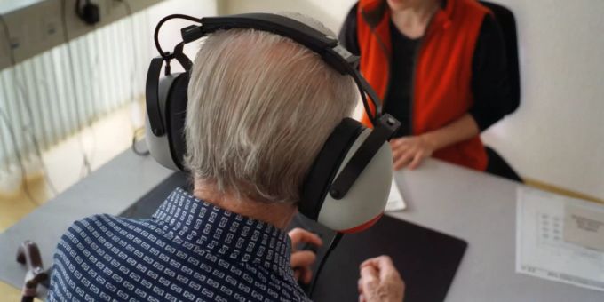 Eine Pflegerin trainiert in der Abteilung für Geriatrie in einem Activity-Programm das Gehör eines betagten Patienten. Eine Verschlechterung des Gehörvermögens kann ein Anzeichen für Demenz sein. geriatrie gehörverlust demenz anzeichen