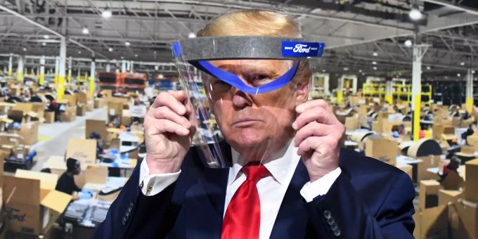 Donald Trump, Präsident der USA, schaut während eines Rundgangs in einem Ford-Werk durch ein Gesichtsvisier vor einem Plakat, das die Fertigung der Visiere zeigt. Coronavirus - USA