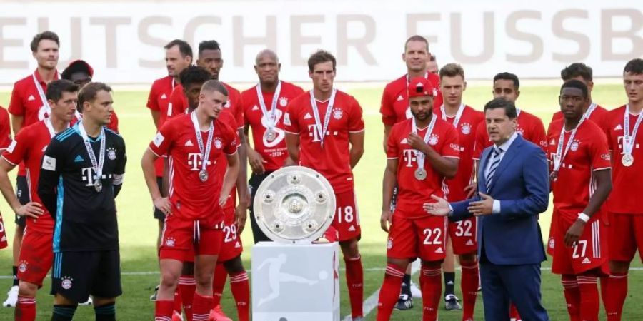 Christian Seifert überreicht nach einer denkwürdigen Saison den Bayern-Profis die Meisterschale. Foto: Kai Pfaffenbach/Reuters-Pool/dpa