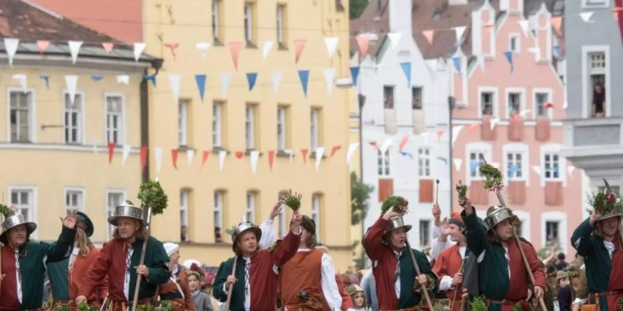Teilnehmer in historischer Kleidung gehen während eines Umzuges der Landshuter Hochzeit durch die Altstadt. Foto: picture alliance / Armin Weigel/dpa
