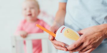 Mensch mit Babyphone, Kind im Hintergrund