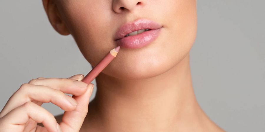 Frau umrandet Lippen mit Lipliner