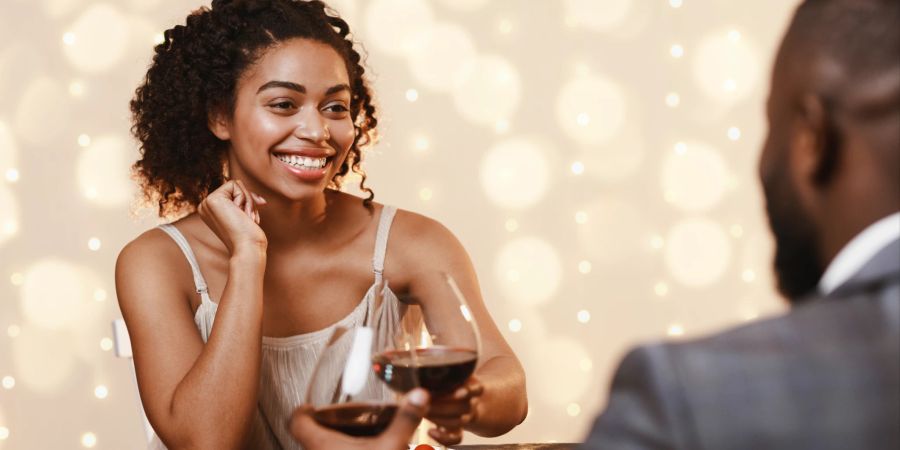 schwarzes paar flirtet beim dinner miteinander, wein, anstossen, heller hintergrund